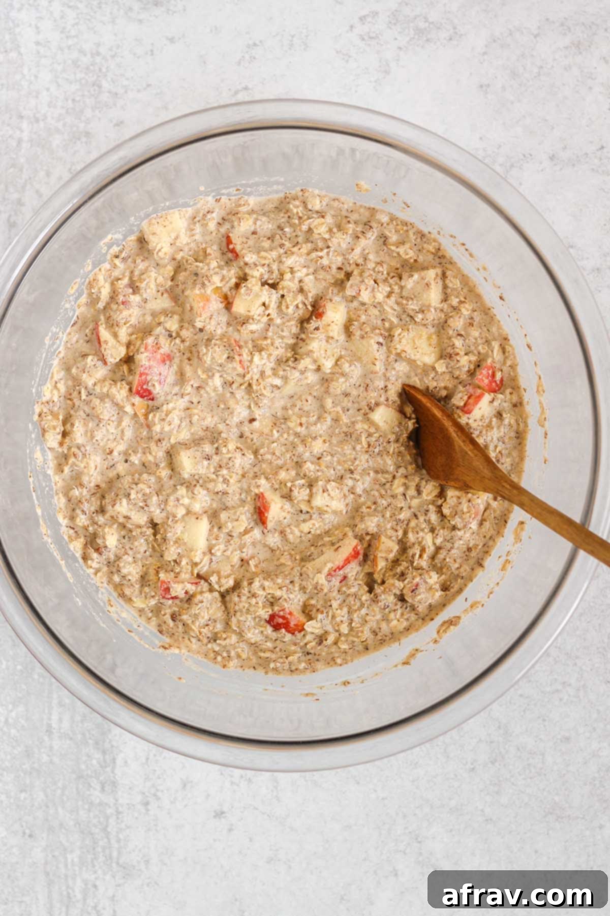 Oatmeal mix with apples in a large glass mixing bowl.