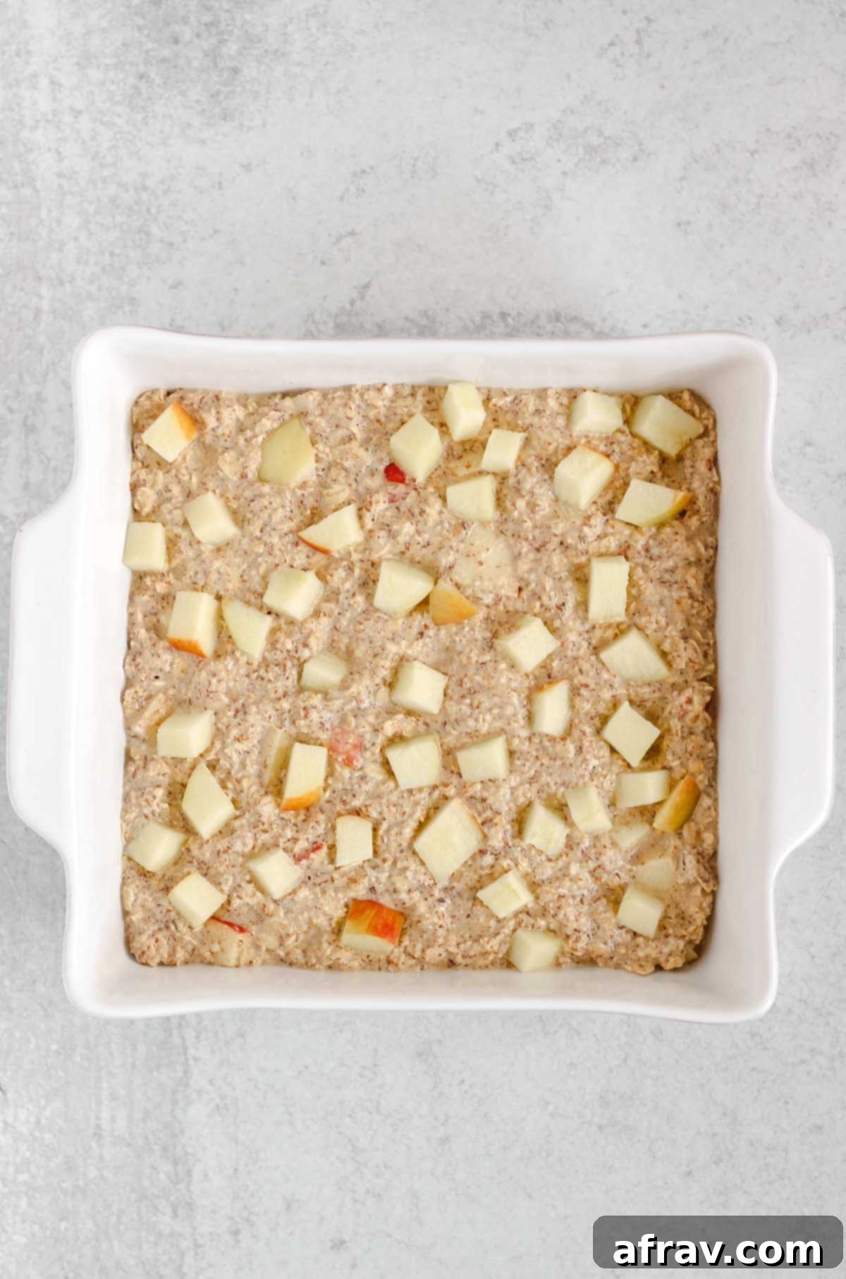 Oatmeal better in a square white baking dish sprinkled with apple pieces.