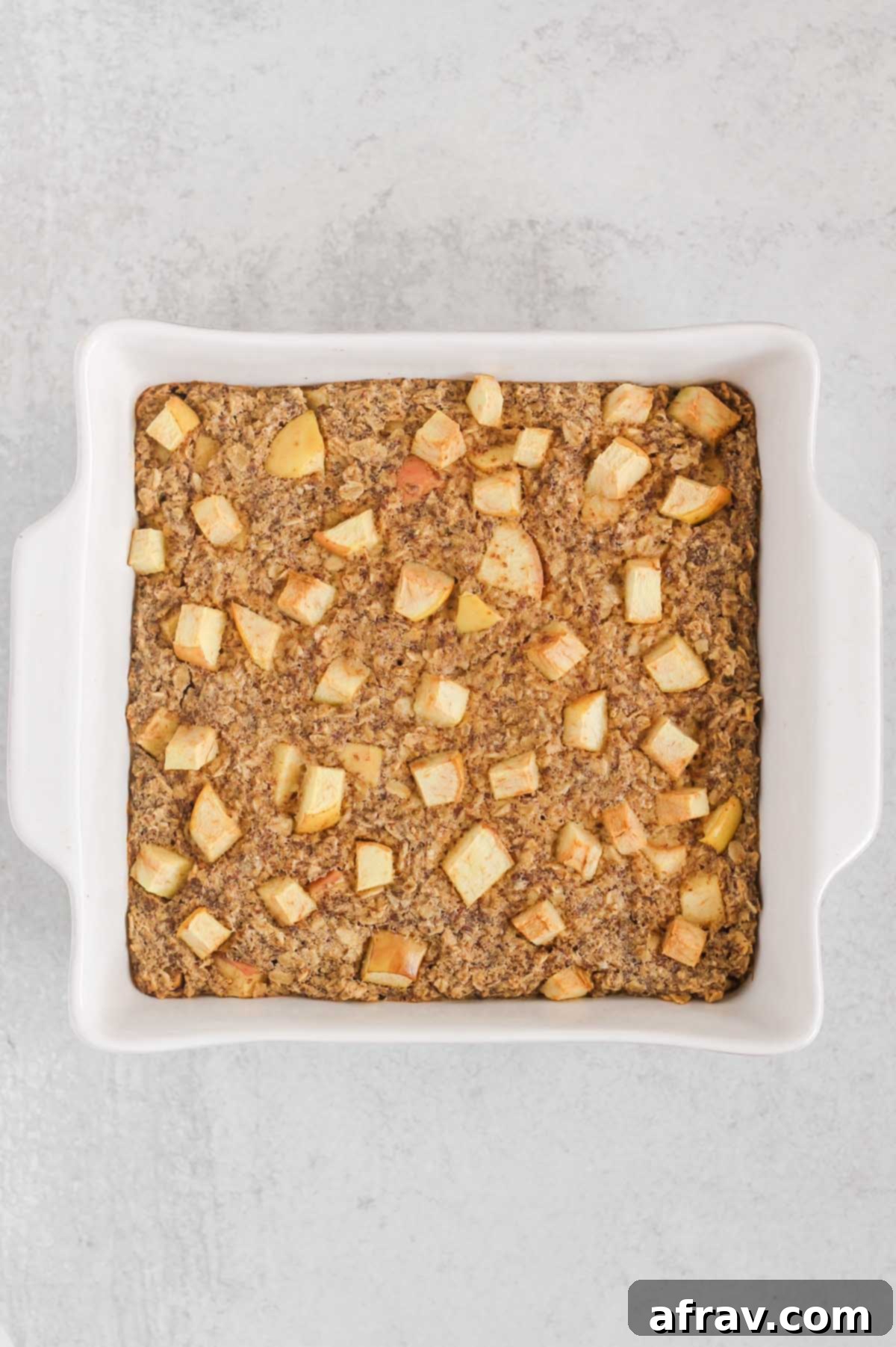 Baked apple cinnamon oatmeal in a square white baking dish.