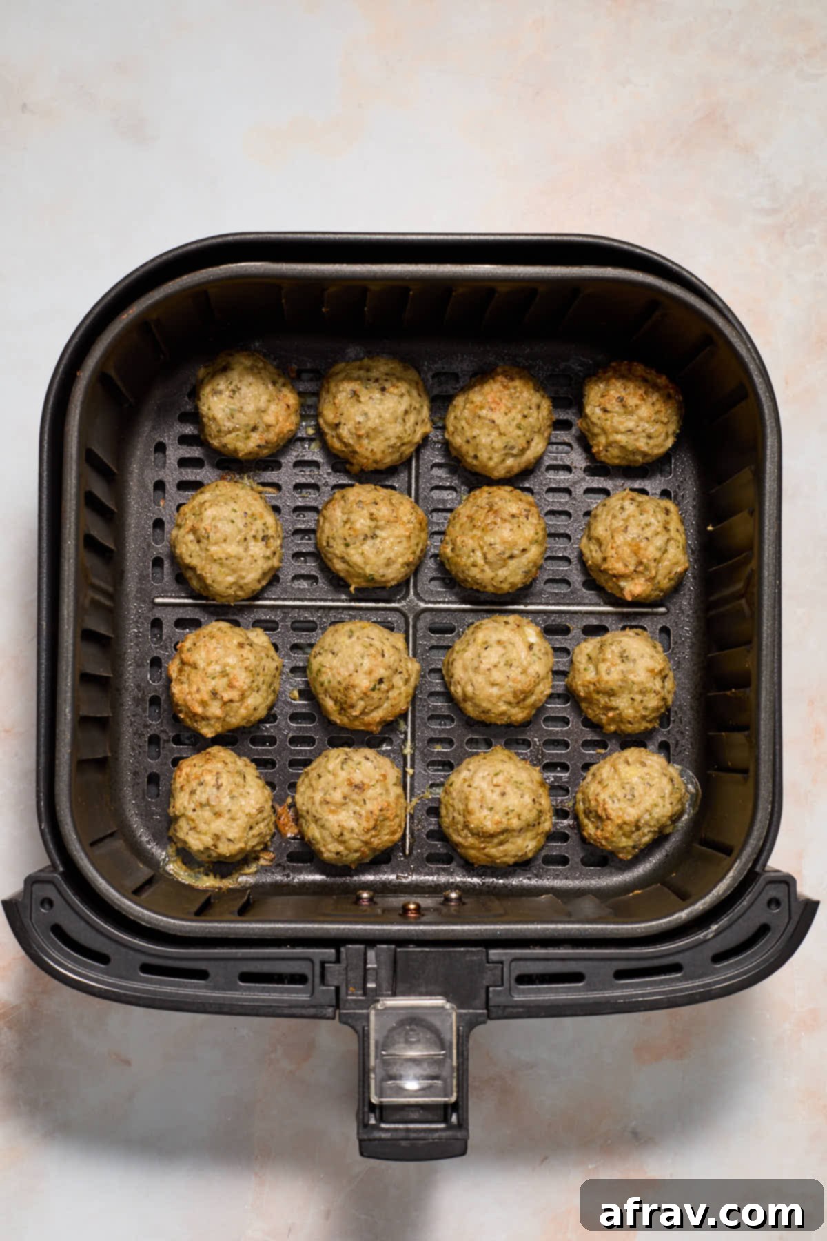 Cooked meatballs in the air fryer basket.