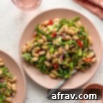 Zesty Tuna and White Bean Medley 2 White bean tuna salad arranged on a pink plate with a pink napkin, glass and pinch bowl off to the side.