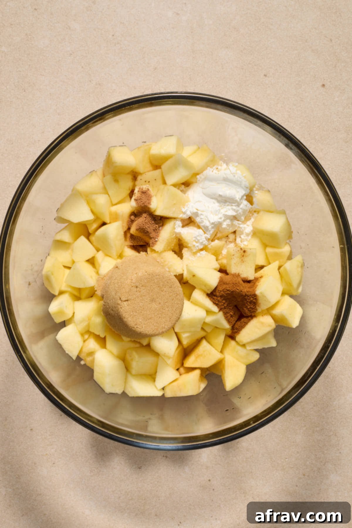Gluten-Free Almond Flour Apple Pecan Crisp 6 Chopped apples and other filling ingredients in a large glass bowl, ready for mixing.