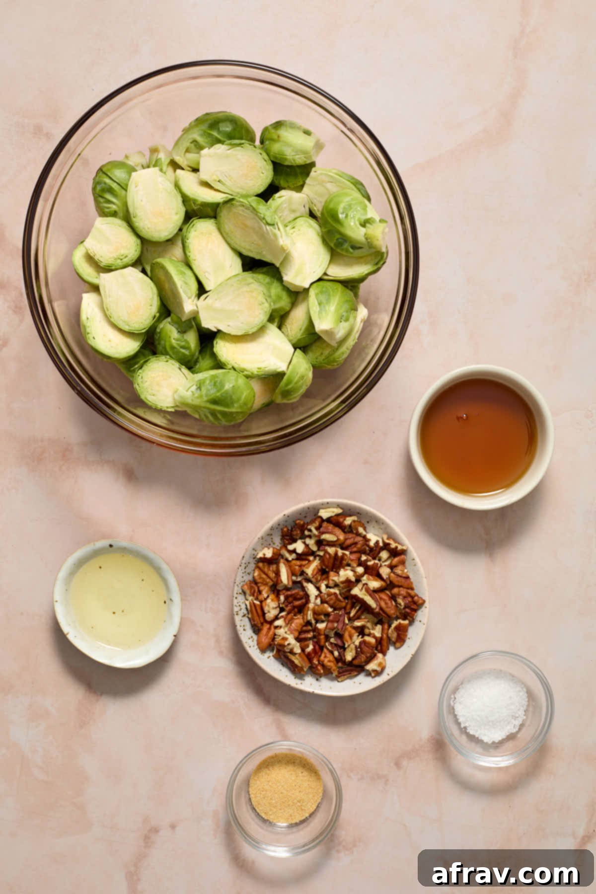 Individual bowls containing raw Brussels sprouts, pecans, and maple syrup, ready for cooking.