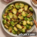 Air fryer maple pecan Brussels sprouts served in a grey bowl with a serving spoon, showcasing the final dish.