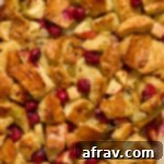 Close up view of baked apple cranberry stuffing with a serving spoon inserted into it.