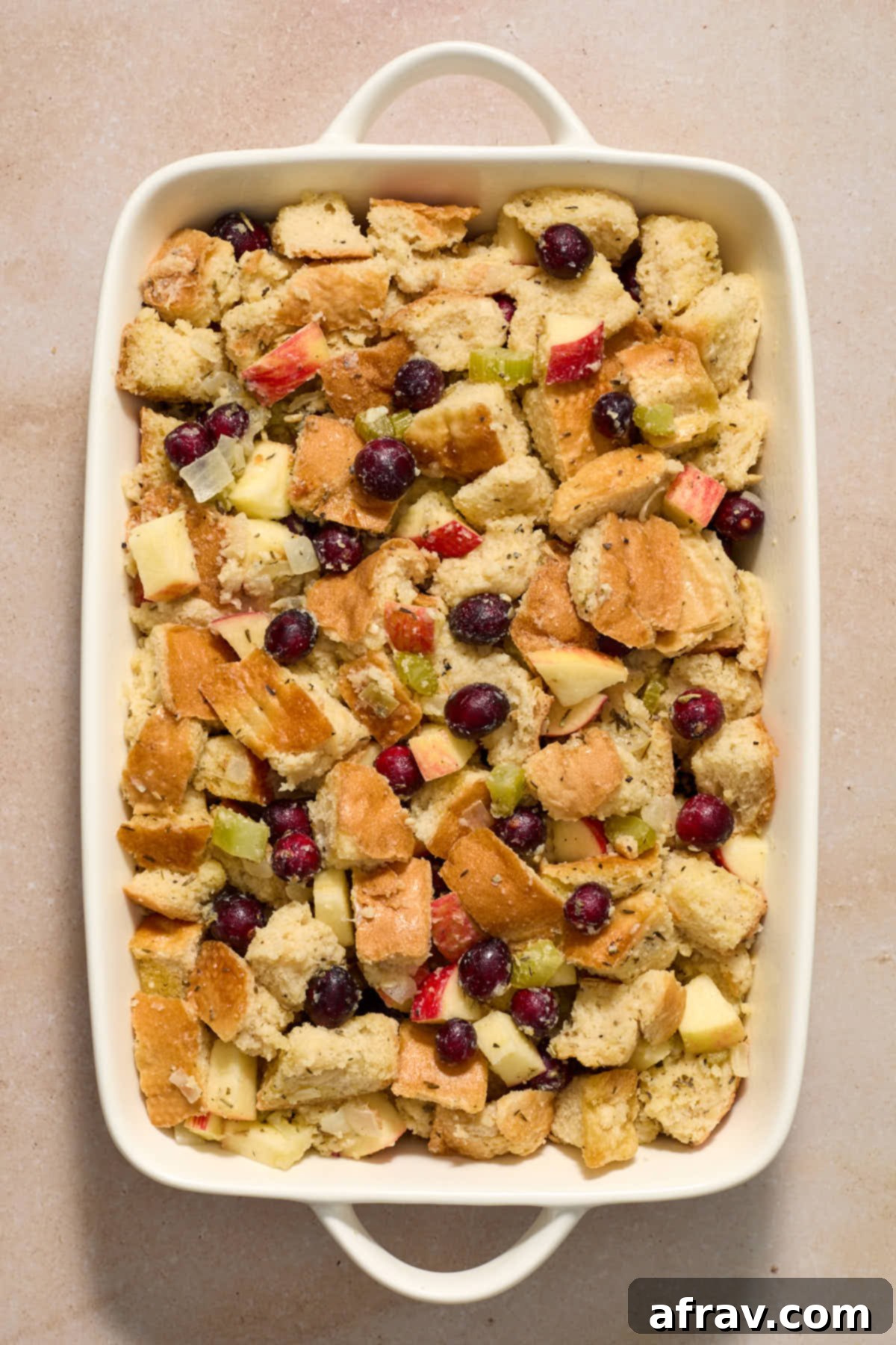 Festive Apple Cranberry Stuffing 10 Stuffing mixture spread out in a white baking dish.