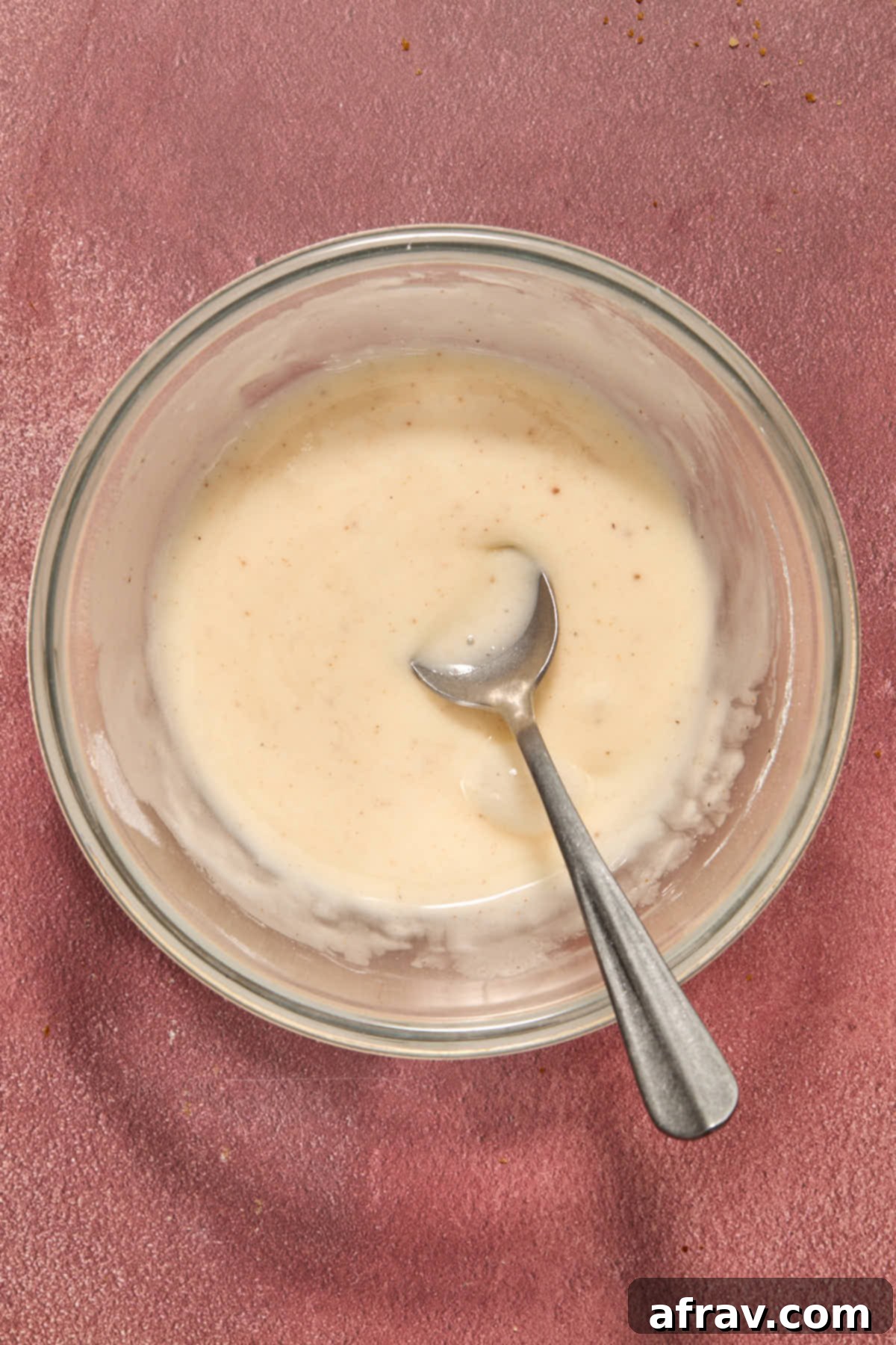 Eggnog glaze stirred together in a small bowl with a spoon.