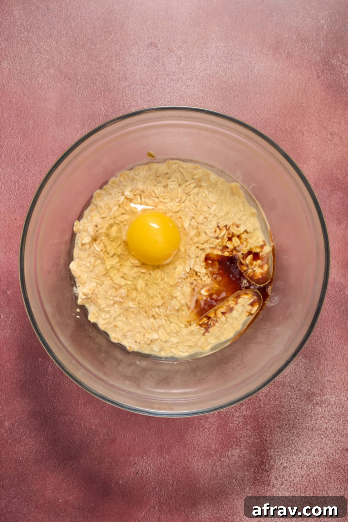 Eggs, oil, vanilla and sugar added to the oat/eggnog mixture in a glass bowl.