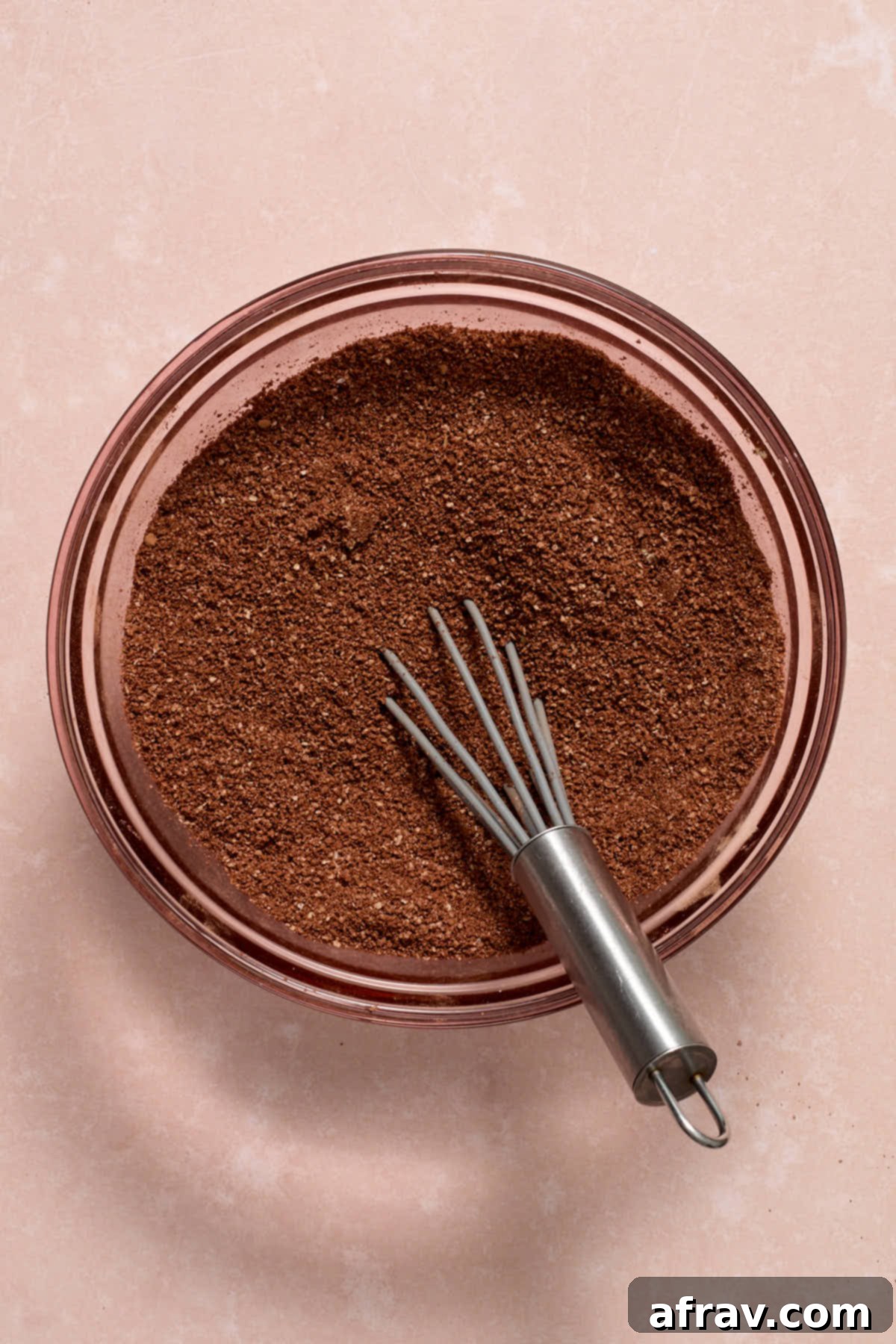 A glass bowl containing cocoa and other dry ingredients, perfectly whisked together to create a uniform mixture.