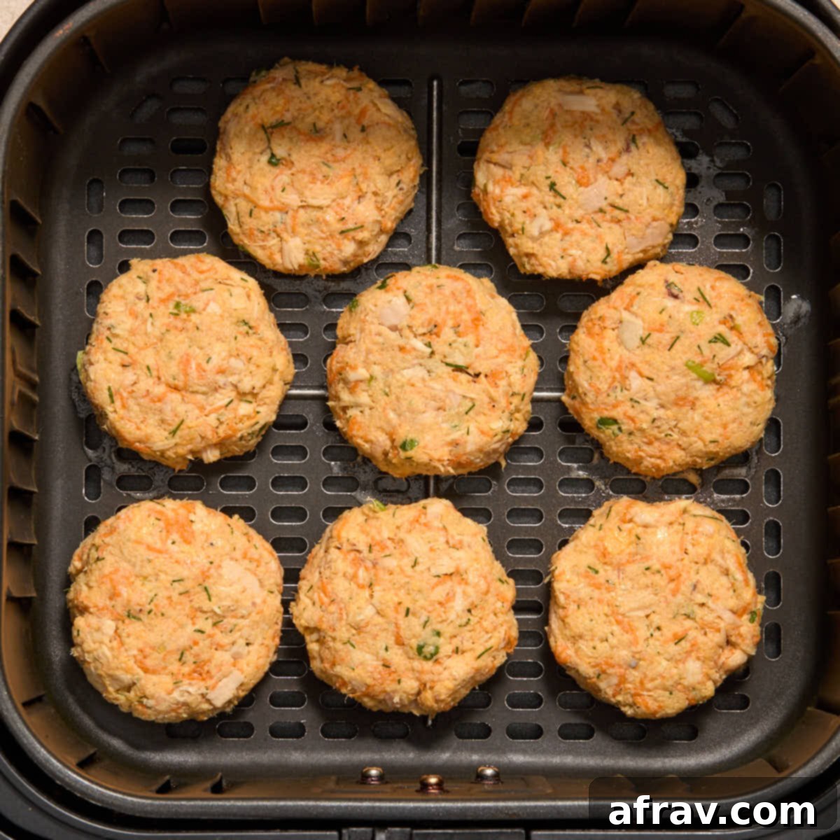 Air Fryer Tuna Cakes with Cheddar & Carrot Zest 7 Several shaped tuna patties arranged in a single layer in an air fryer basket.