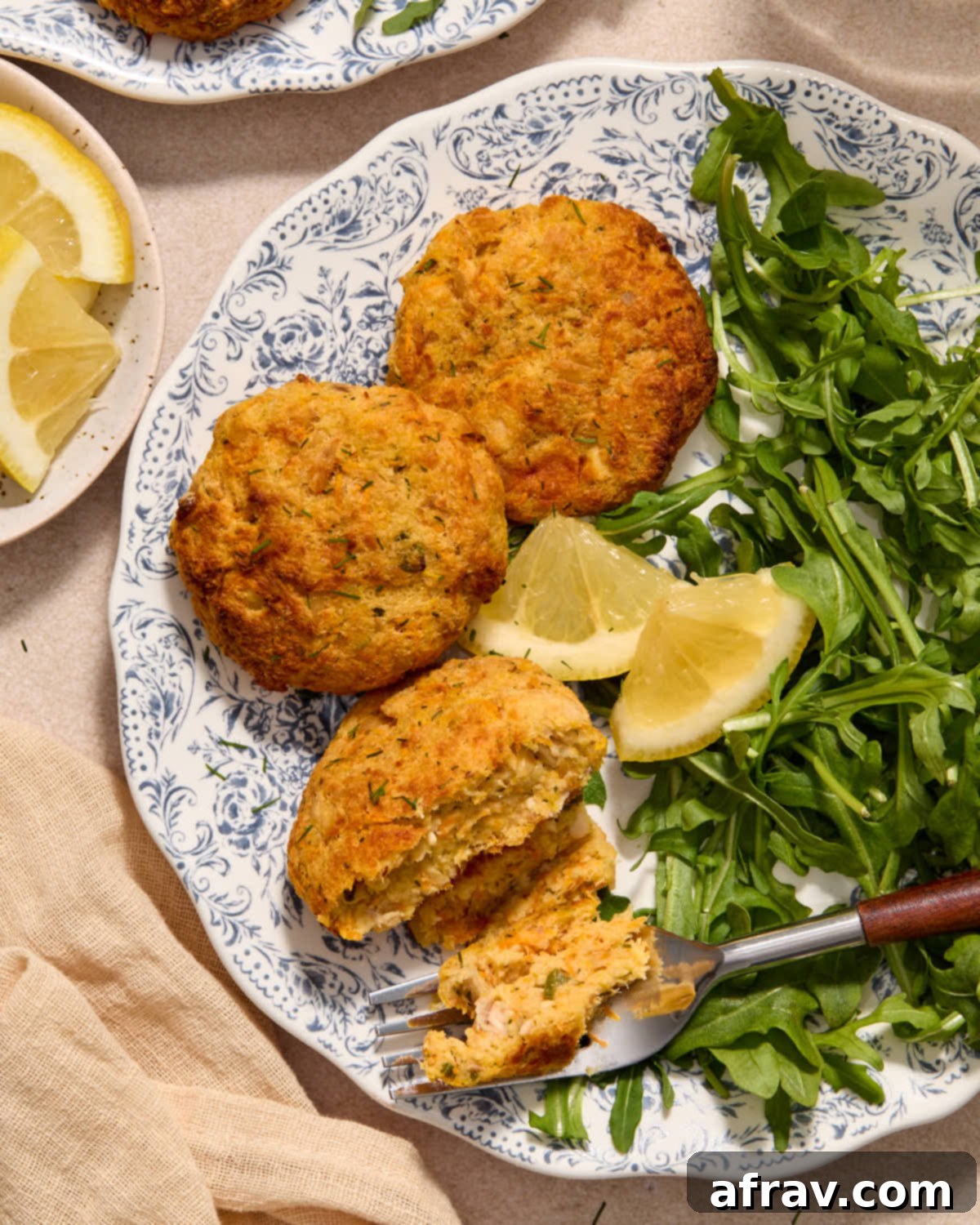Air Fryer Tuna Cakes with Cheddar & Carrot Zest 9 Air fried tuna cakes served on a plate with lemon wedges and greens.