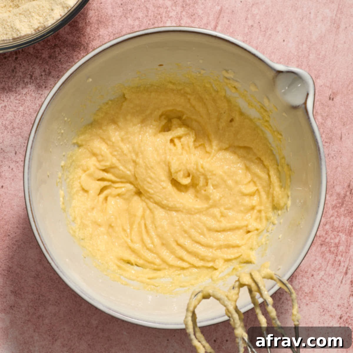 Almond Dream Bars: Chewy, Creamy, and Irresistibly Good 6 Eggs and extracts mixed into the butter/sugar mixture in a white bowl.