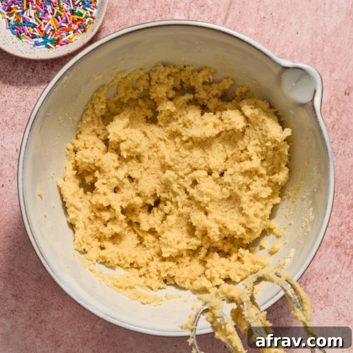 Almond Dream Bars: Chewy, Creamy, and Irresistibly Good 7 Cookie dough batter in a white bowl with a dish of sprinkles on the side.