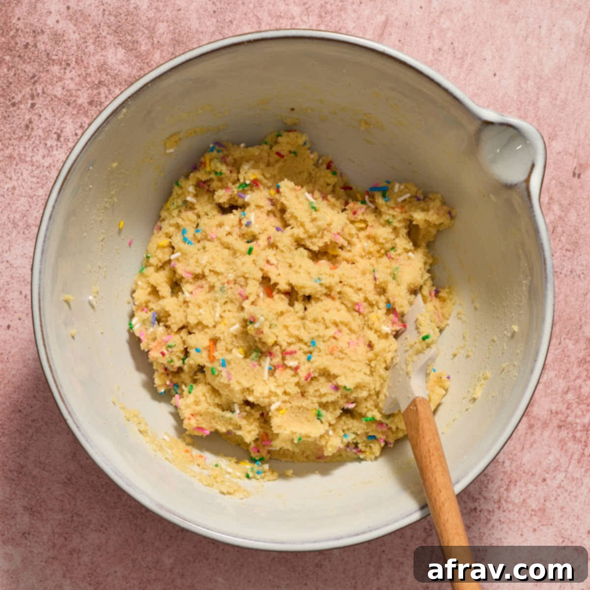 Almond Dream Bars: Chewy, Creamy, and Irresistibly Good 8 Sprinkles mixed into the cookie dough in a bowl with a spatula.