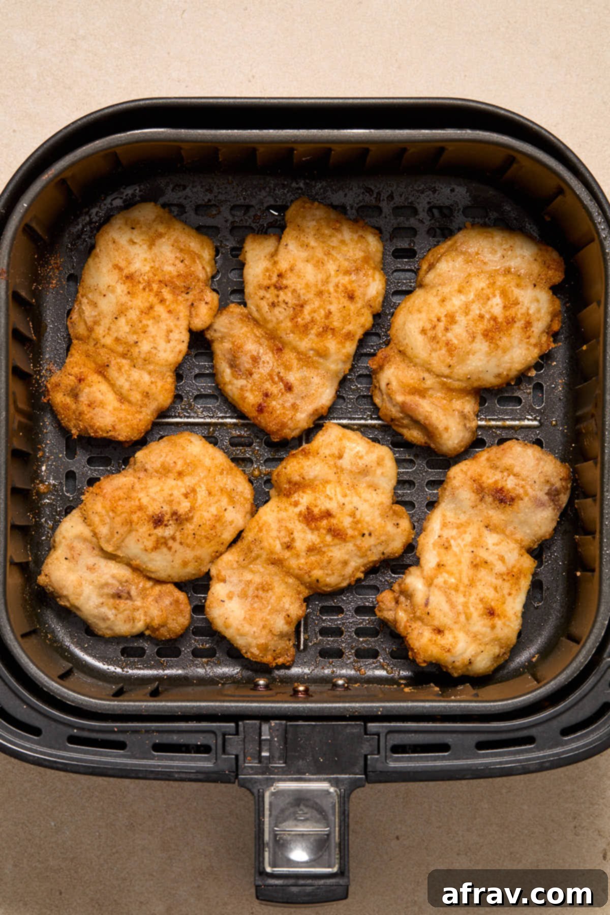 Honey Garlic Glazed Chicken Thighs: An Air Fryer Delight 5 Six air fried boneless skinless chicken thighs in an air fryer basket.