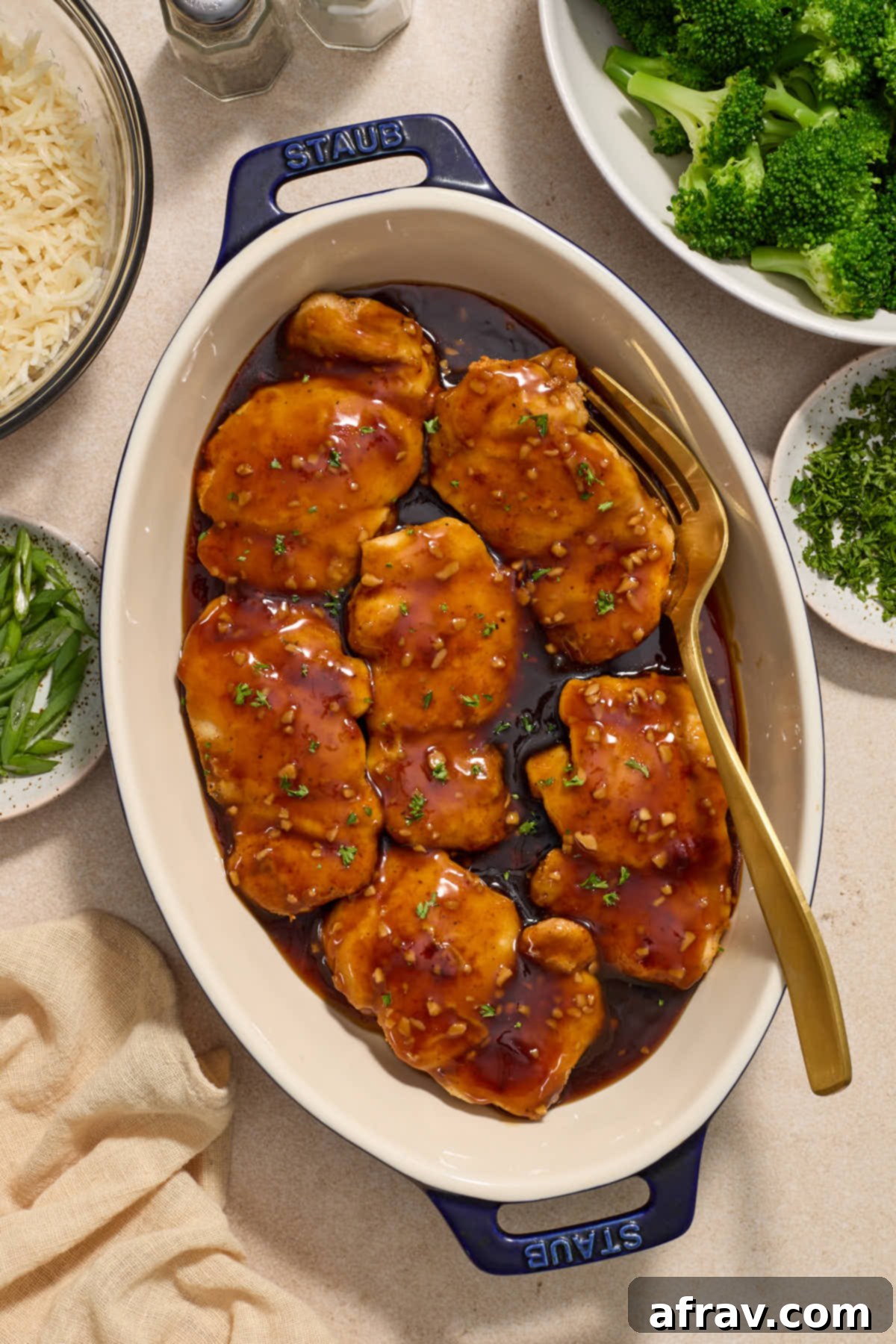Honey Garlic Glazed Chicken Thighs: An Air Fryer Delight 8 Chicken thighs covered in sauce in an oval dish with garnishes, broccoli and rice on the side.