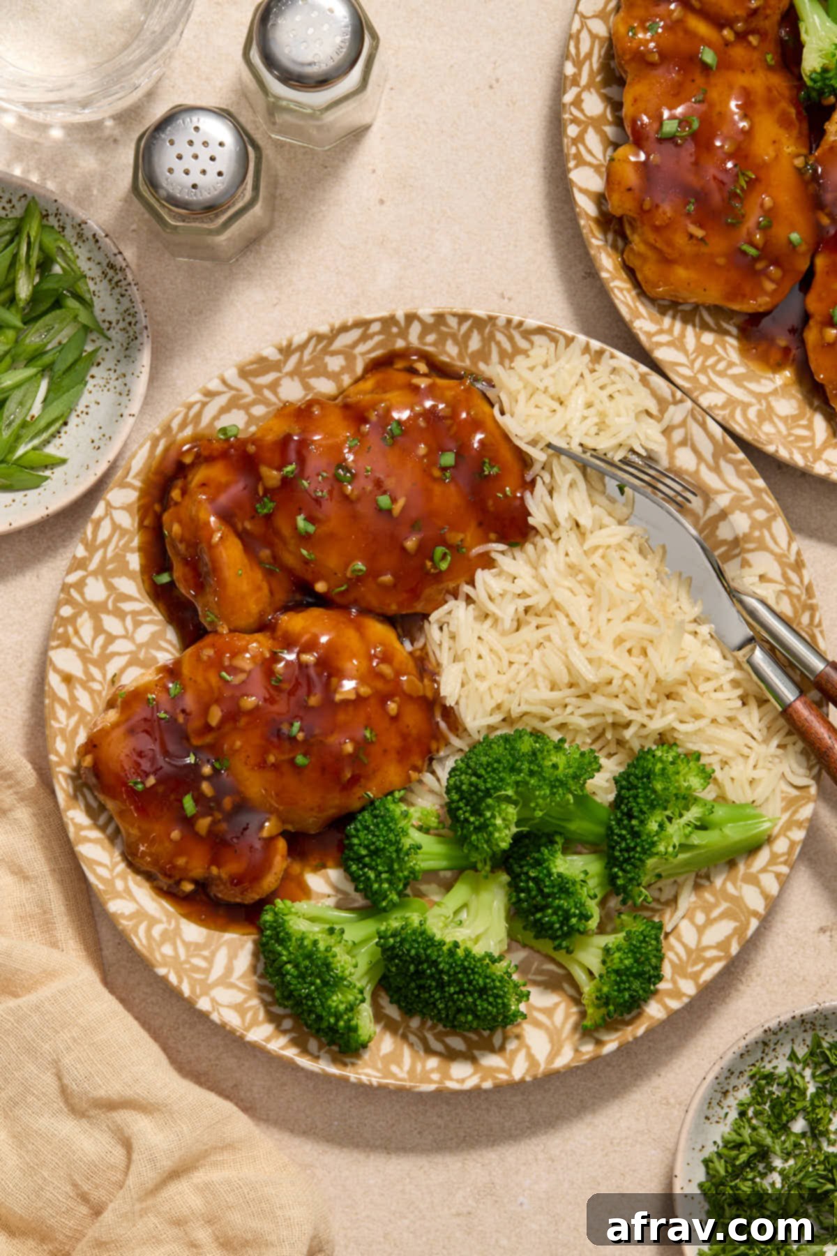 Honey Garlic Glazed Chicken Thighs: An Air Fryer Delight 9 Close up of air fryer chicken thighs covered in sauce served on a plate with green onion on top.