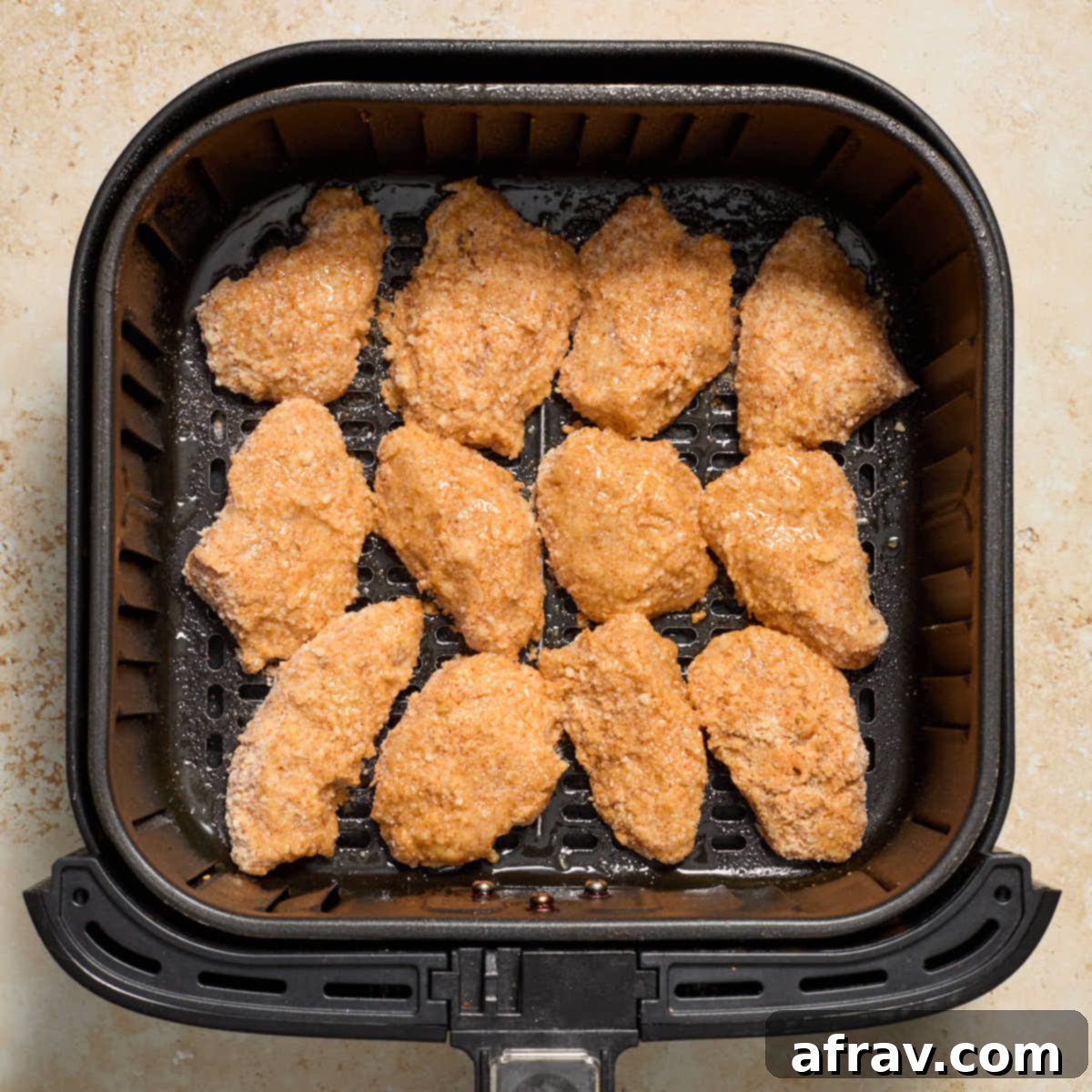 Garlic Parmesan Air Fryer Chicken Bites 12 Tops of chicken sprayed with oil in air fryer basket.