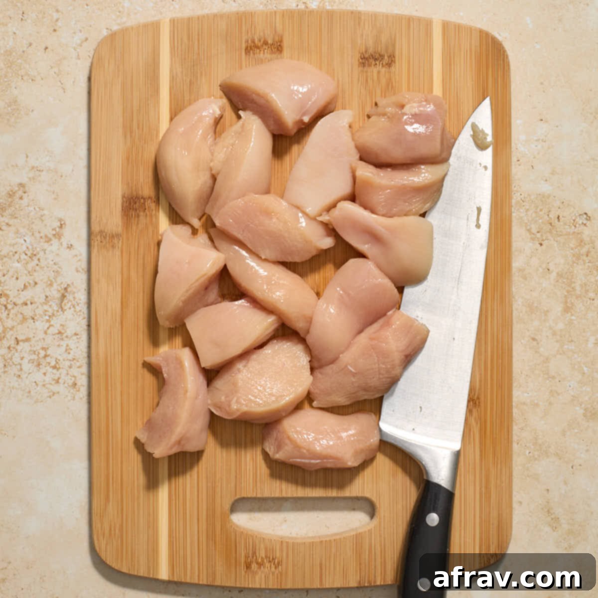 Garlic Parmesan Air Fryer Chicken Bites 4 Chicken breasts sliced into pieces on a wooden cutting board.