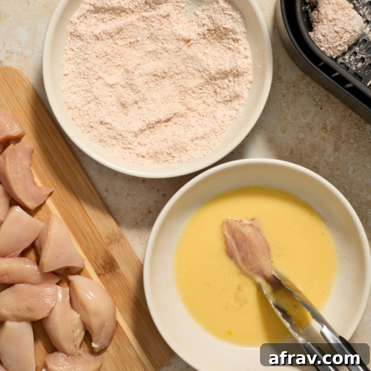 Garlic Parmesan Air Fryer Chicken Bites 7 A piece of chicken being dipped in the egg mixture.