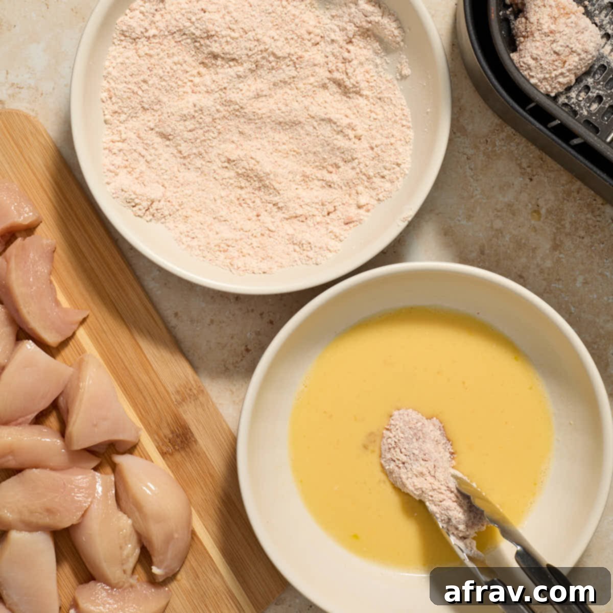 Garlic Parmesan Air Fryer Chicken Bites 9 Piece of floured chicken being dipped in egg again.