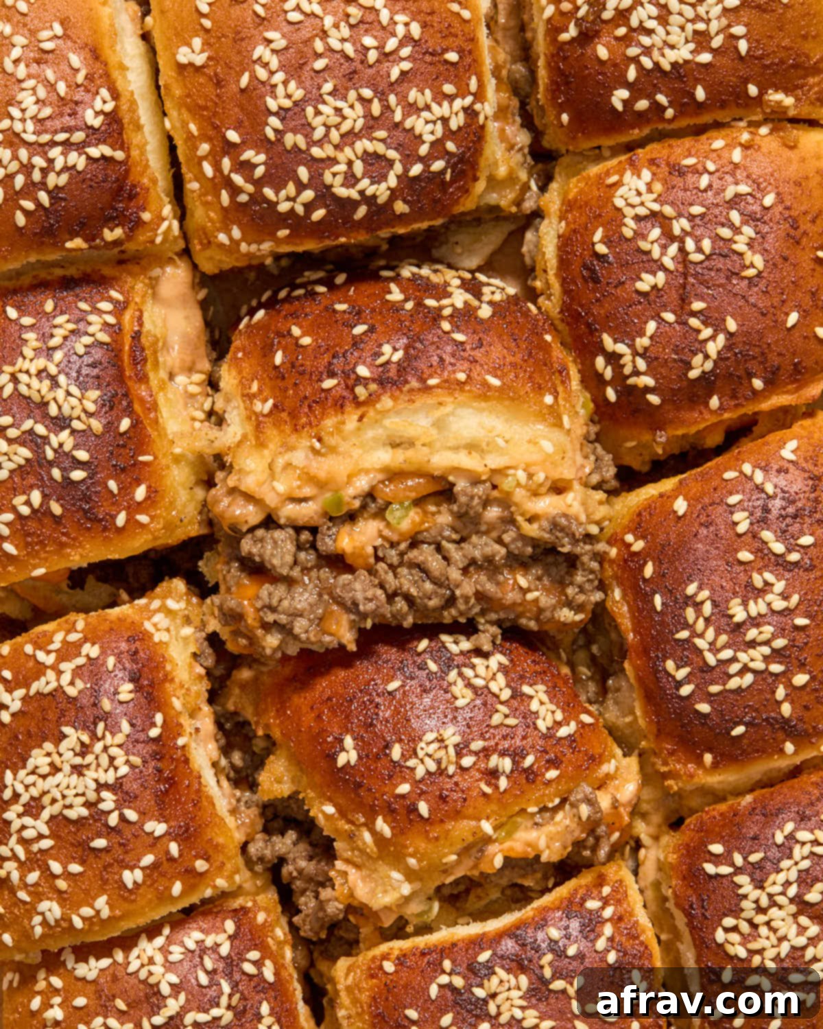 Air Fryer Mini Cheeseburgers 2 Overhead view of assembled ground beef sliders on parchment paper in an air fryer.
