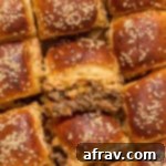 Close up of ground beef sliders with one turned on its side to show the ground beef and cheese filling.