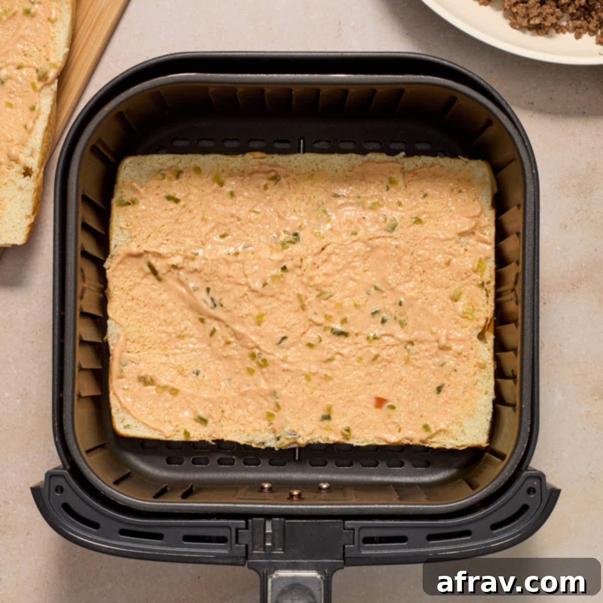 Air Fryer Mini Cheeseburgers 7 The bottom half of the sweet rolls in the air fryer basket with burger sauce spread on it.